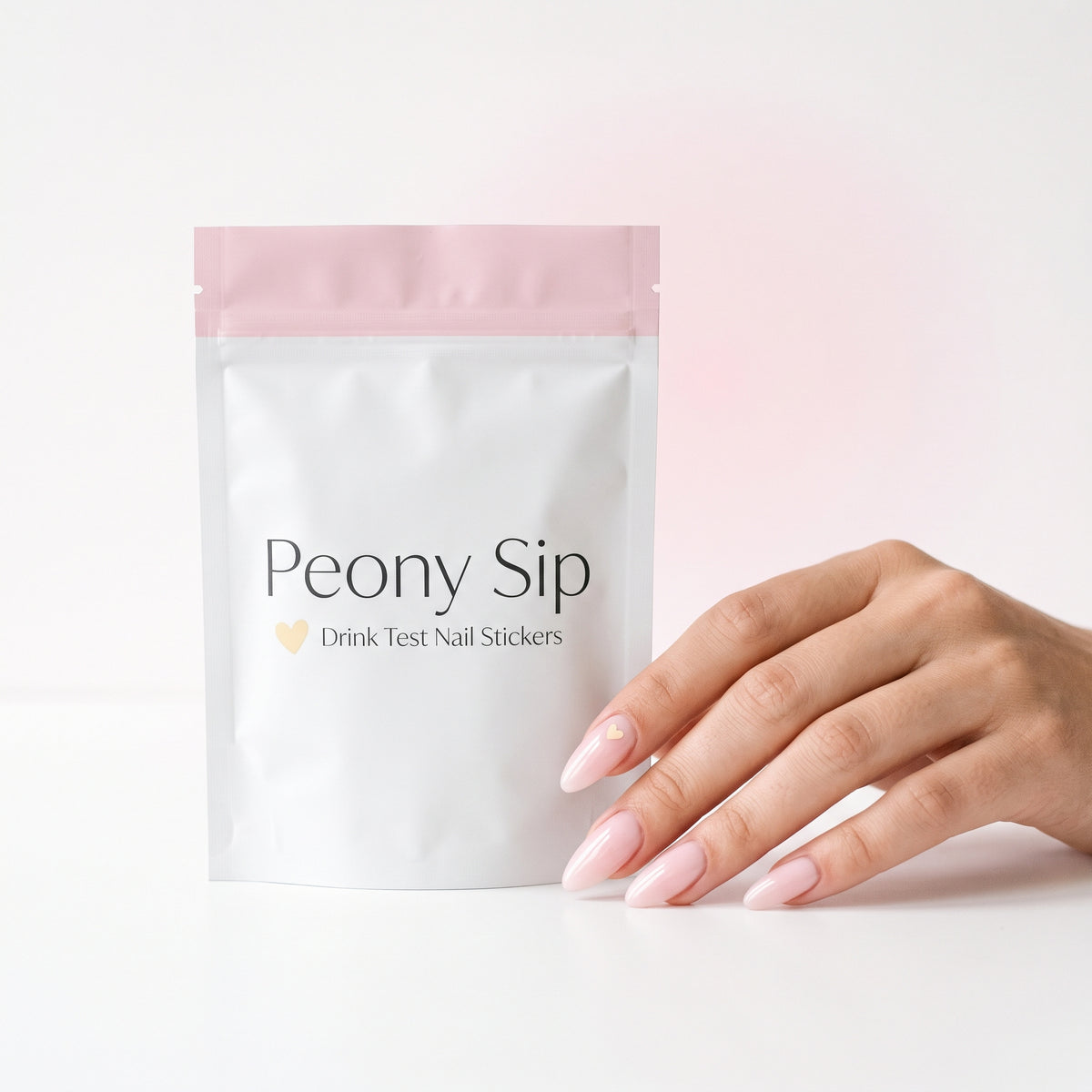 Peony Sip pouch next to a hand with a heart sticker on one nail